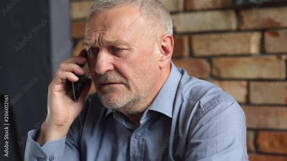 Gray-haired man sitting in the workplace and talking on mobile phone.
Gray-haired man sitting in the workplace and talking on mobile phone.