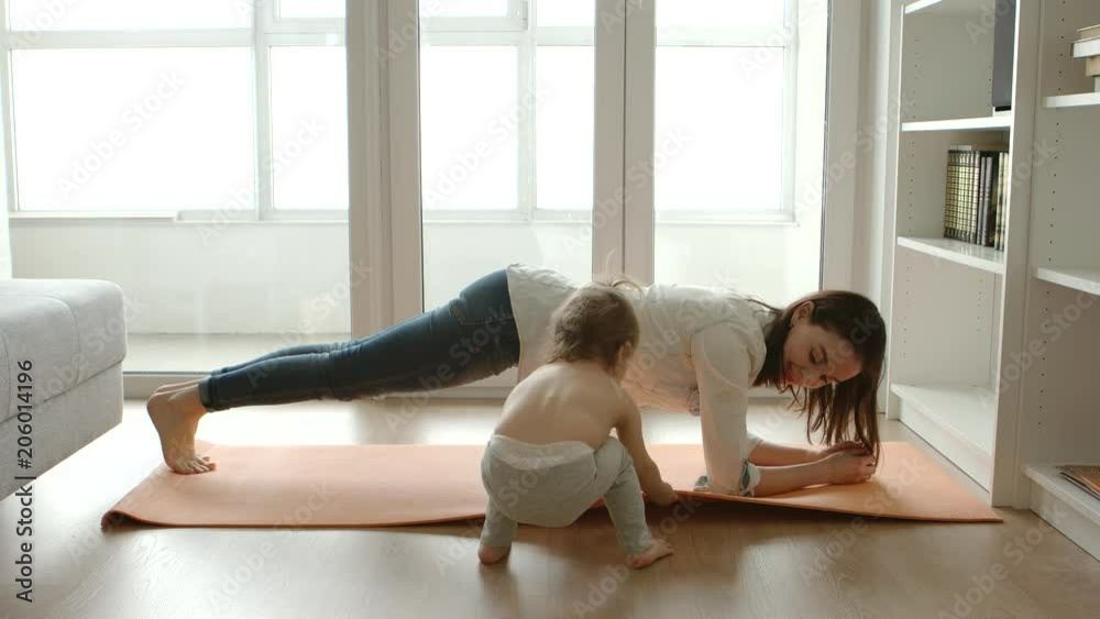 A little daughter pulls a yoga mat for her mother
