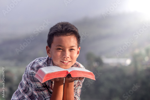 boy holding the holy bible and smiling.