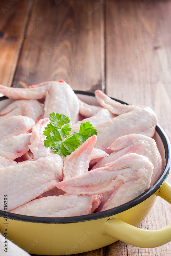 Raw chicken wings in an enamel frying pan, selective focus