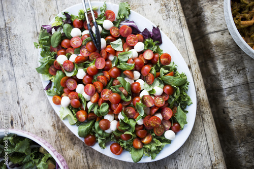 Bird's eye view of cherry tomato, white cheese, and green leaf salad