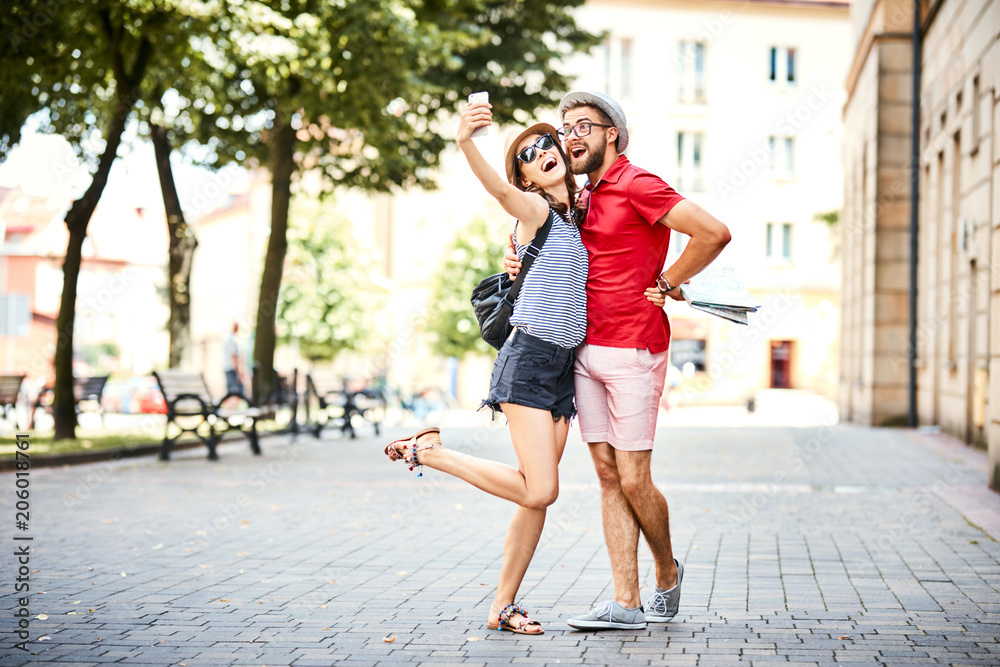 Couple taking selfie together while on walk in the city during summer
