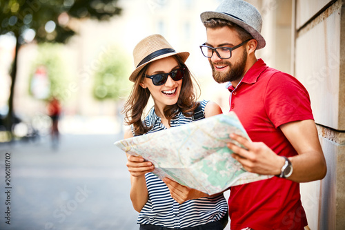 Fototapeta Young couple looking at map while on vacation during summer together