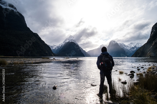 A backpacker man with jacket and beanie enjoying with the stunning scenery of the ford land at Milford Sound, New Zealand