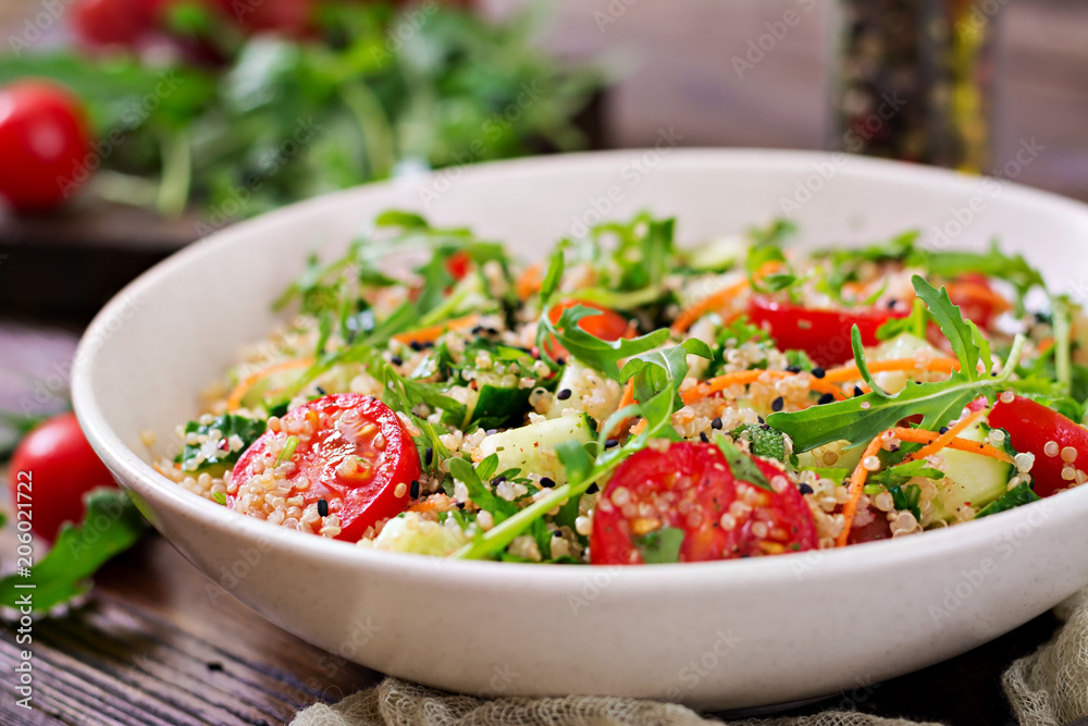 Salads with quinoa, arugula, radish, tomatoes and cucumber in bowl on wooden background. Healthy food, diet, detox and vegetarian concept. Salads with quinoa, arugula, radish, tomatoes and cucumber in bowl on wooden background. Healthy food, diet, detox and vegetarian concept.