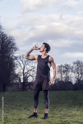 Male runner drinking water after an evening run on a cool winters evening