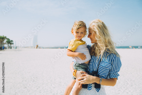 Young mother and happy little son at sandy beach in Dubai, UAE © Tetiana