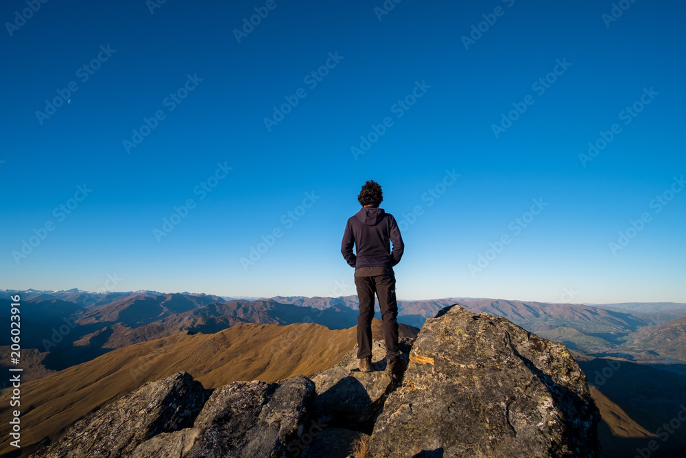 A young Asian man enjoying looking at the stunning scenery on the high mountain before sunset.