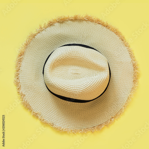 Straw beach sun-hat on yellow. Female outfit for heat. Square image. Minimal. Summer concept.