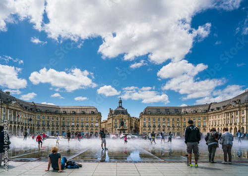 Bordeaux, France, 10 may 2018 : Tourists visiting the Place de la Bourse seen from the boulevard with in front the mirror fountain: 'Mirroir d'eau' photo