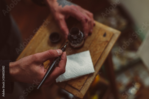 Hands of artist holding pen and ink for drawing on wooden table