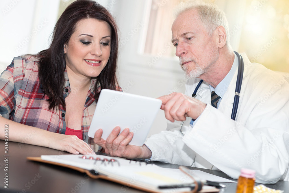 Doctor showing reports on digital tablet to patient, light effect Doctor showing reports on digital tablet to patient, light effect