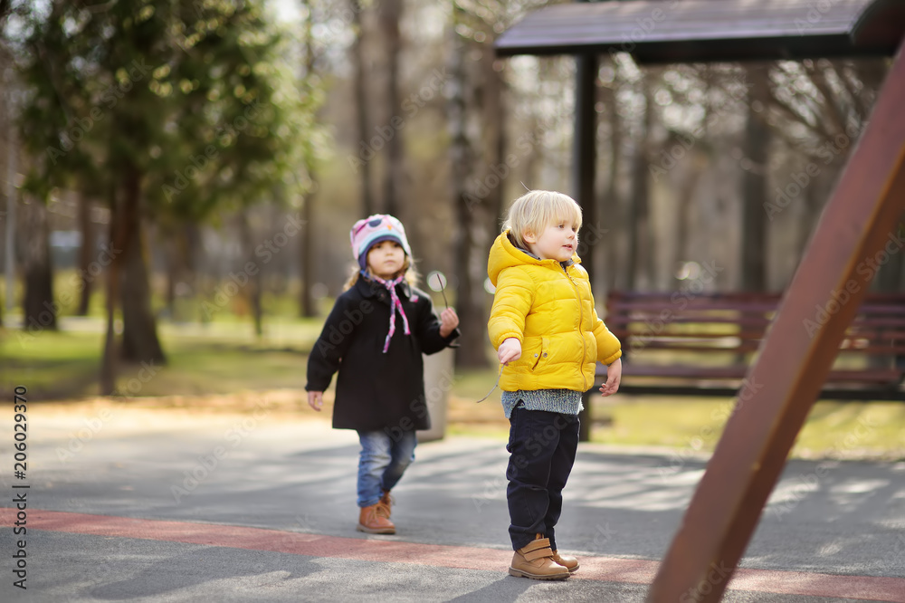 Little boy and girl having fun on outdoor playground on spring or fall day Little boy and girl having fun on outdoor playground on spring or fall day