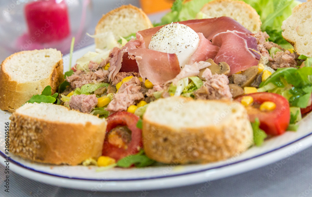 Close-up of a fresh salad on a plate. Healthy food. Slices of bread, lettuce, tomato, mozzarella, corn, mushrooms and slice of ham Close-up of a fresh salad on a plate. Healthy food. Slices of bread, lettuce, tomato, mozzarella, corn, mushrooms and slice of ham