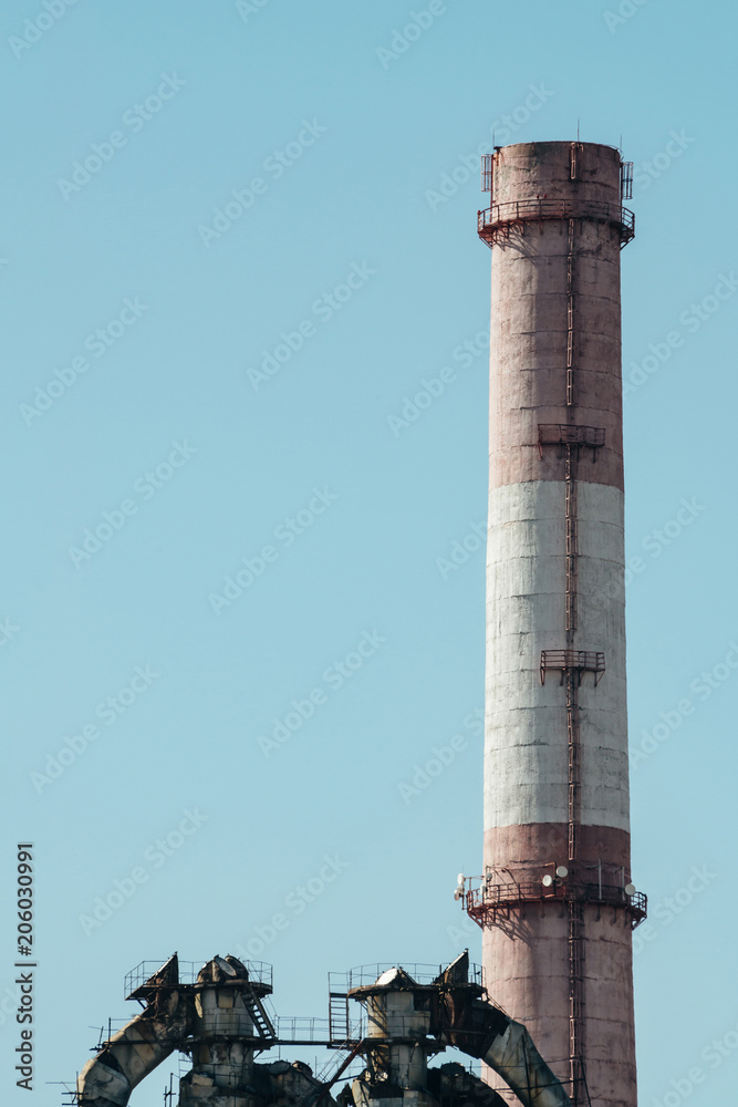 High red and white striped tube on background clear blue sky close-up. Thermal power plant with copy space.