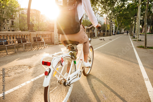 Back view image of young lady on bicycle on the street.