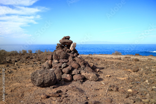 A pyramidal pile of lava stones by the ocean. tenerife.
