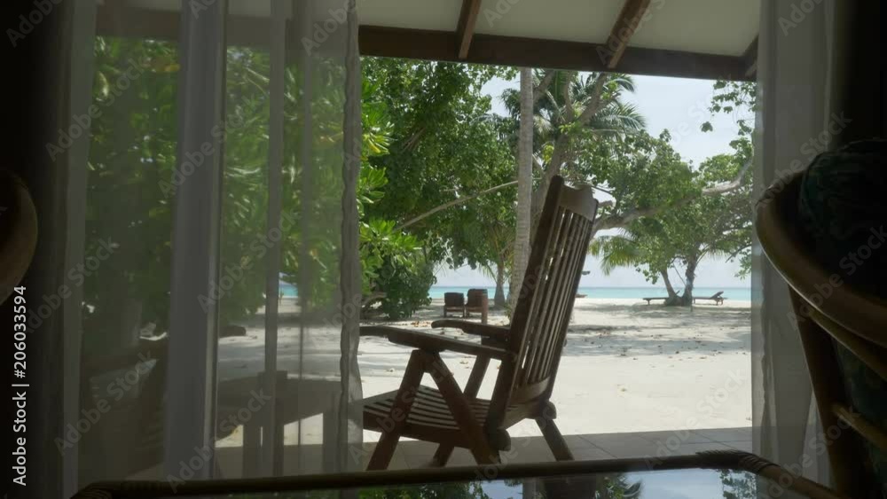 A woman sitting in a sun lounger on the terrace and looking at the beautiful beach. A woman sitting in a sun lounger on the terrace and looking at the beautiful beach.