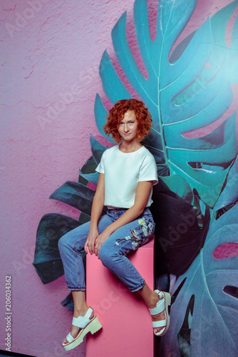 Beautiful sexy red hair smiling woman wearing high waist jeans and white t-shirt, high heels posing in studio. Colorful bright background. Isolated on white. Full-length portrait. Studio shot.