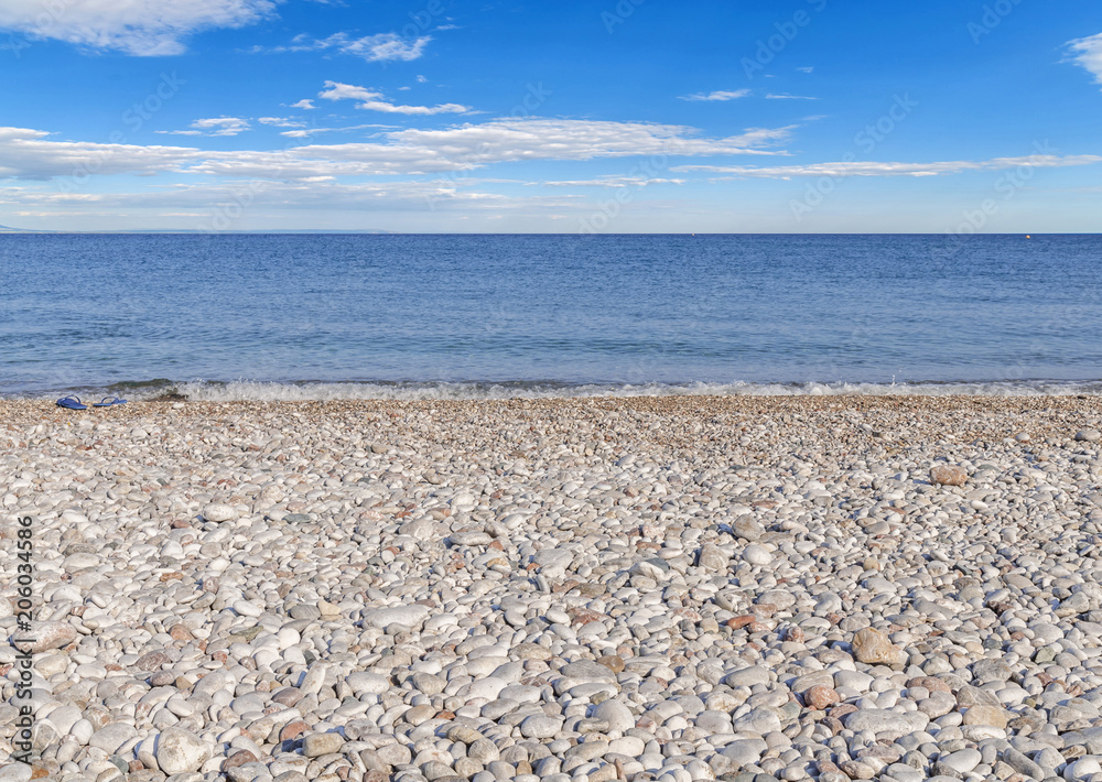 Pebble stone beach with cloudy blue sky Pebble stone beach with cloudy blue sky