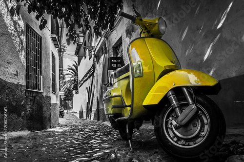 Obraz na plátně Yellow vespa scooter parked in an old empty paved street