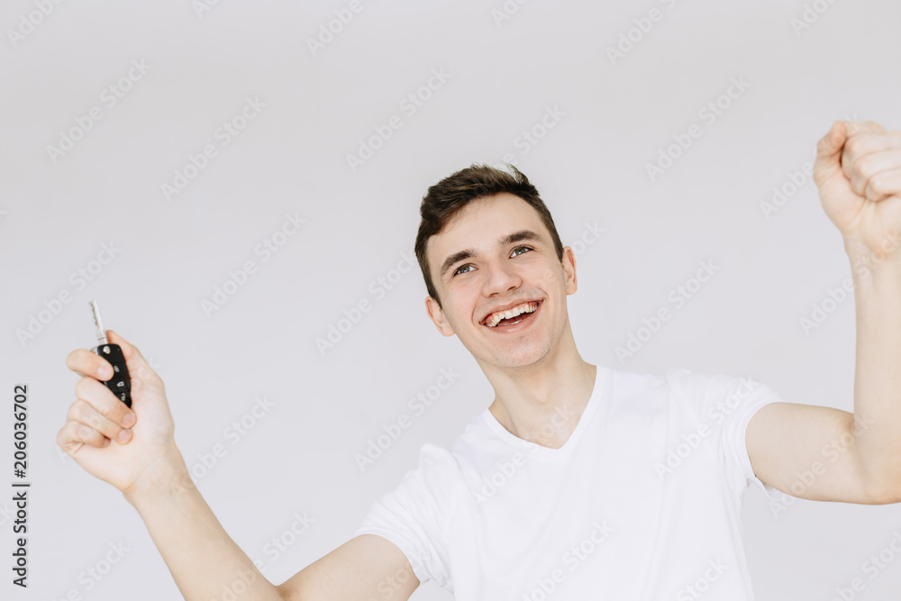 Young man holds car keys and smiles. Enjoy buying a car. Іsolated white background Young man holds car keys and smiles. Enjoy buying a car. Іsolated white background