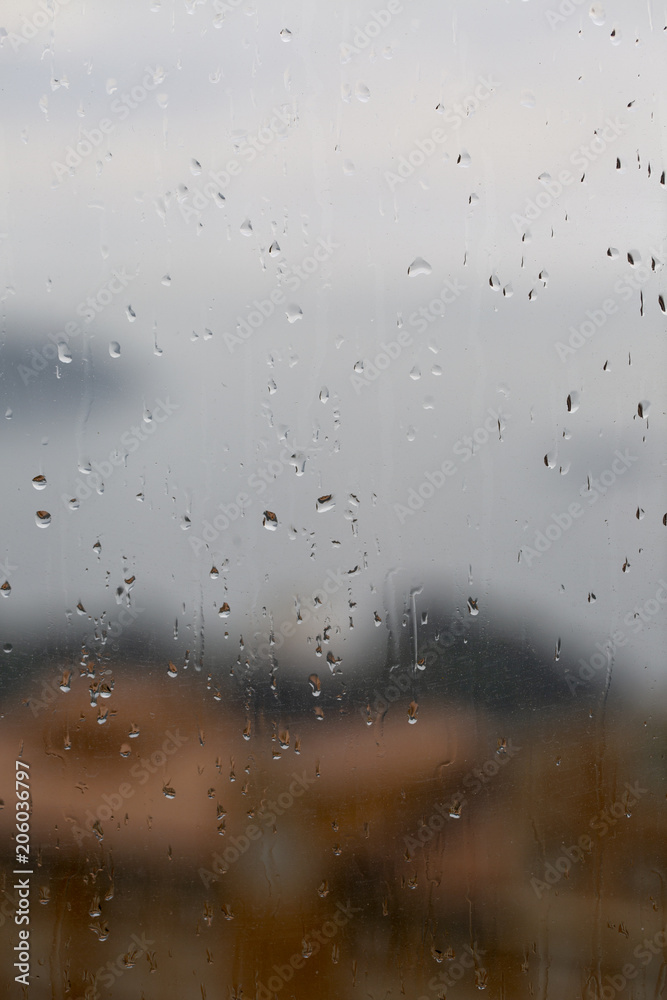 View of the sea and the city through a wet glass. Raindrops.