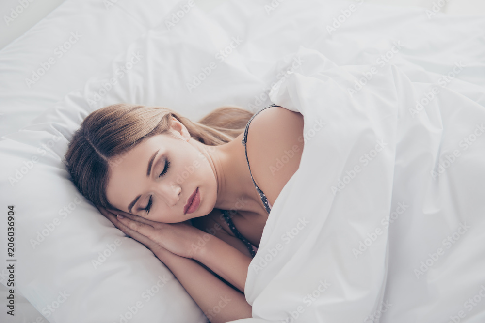Top view portrait of pretty, serious, stylish, charming, nice, cute, cheerful girl with makeup lying in bed under blanket, having a good sleep with close eyes, putting hands under cheek Top view portrait of pretty, serious, stylish, charming, nice, cute, cheerful girl with makeup lying in bed under blanket, having a good sleep with close eyes, putting hands under cheek