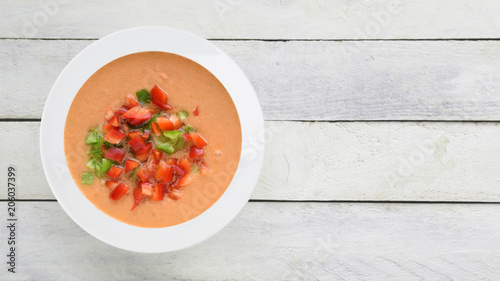 Andalusian gazpacho served in a white plate on a wooden table. Top view and empty copy space for Editor's text.