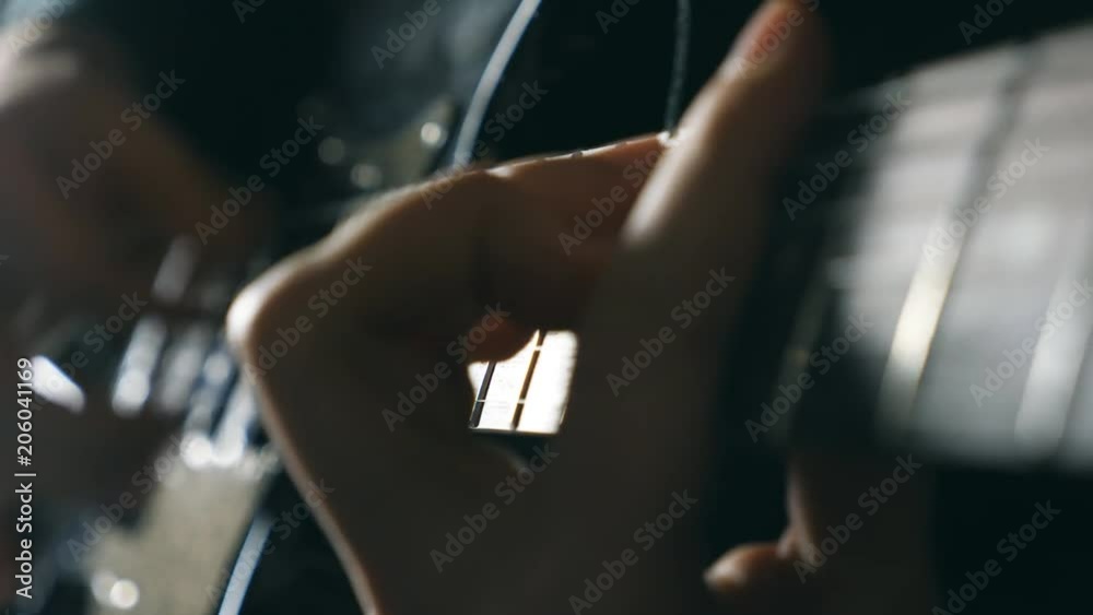 Hands of male musician playing at electric guitar. Mens arms plays solo of rock music. Close up fingers of guitarist at the strings. Beautiful black background at studio. Slow motion Close up Hands of male musician playing at electric guitar. Mens arms plays solo of rock music. Close up fingers of guitarist at the strings. Beautiful black background at studio. Slow motion Close up
