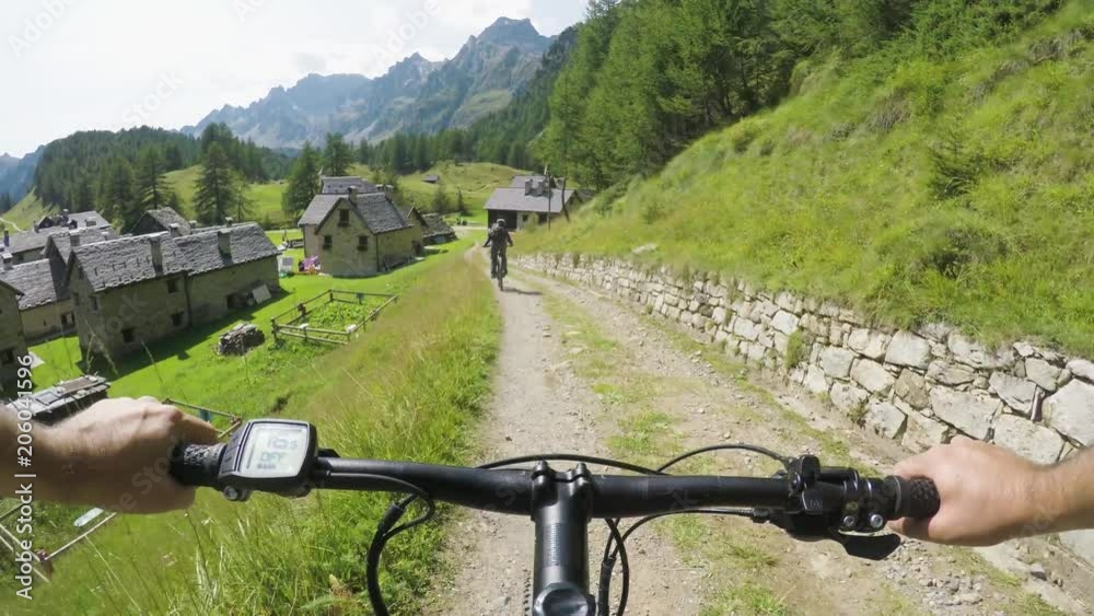 POV man riding e-bike to town village.Mtb action cyclist exploring path near mountains.Electrical bike active people sport travel vacation in Europe Italy Alps outdoors in summer.4k video POV man riding e-bike to town village.Mtb action cyclist exploring path near mountains.Electrical bike active people sport travel vacation in Europe Italy Alps outdoors in summer.4k video