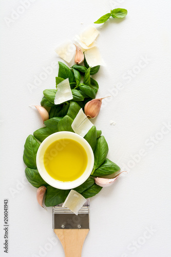 Paint brush and dab of pesto (ingredients for cooking sauce: basil leaves, garlic, parmesan and olive oil). Food art concept. Top view. Flat lay