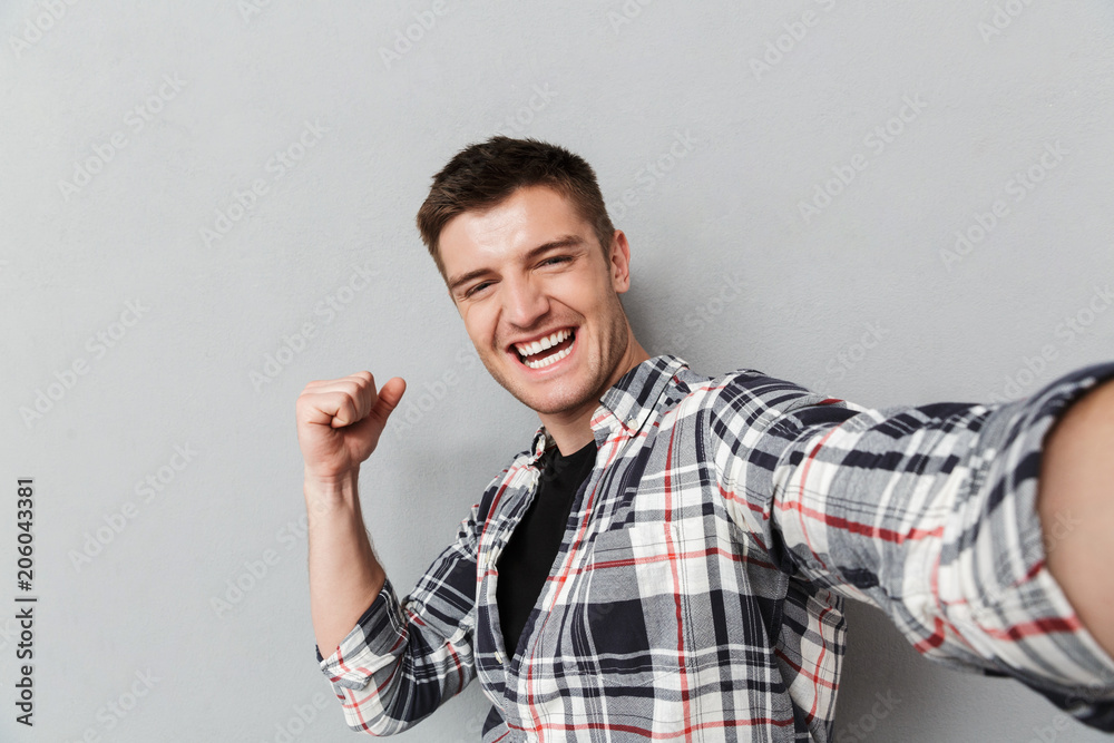 Portrait of an excited young man in plaid shirt taking a selfie Portrait of an excited young man in plaid shirt taking a selfie