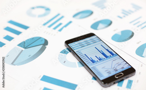 Business charts and graphs on paper and in smartphone
