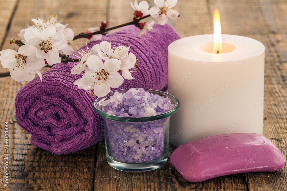 Sea salt in glass bowl, towel for bathroom procedures with flowering branch of apricot tree, soap and burning candle Sea salt in glass bowl, towel for bathroom procedures with flowering branch of apricot tree, soap and burning candle