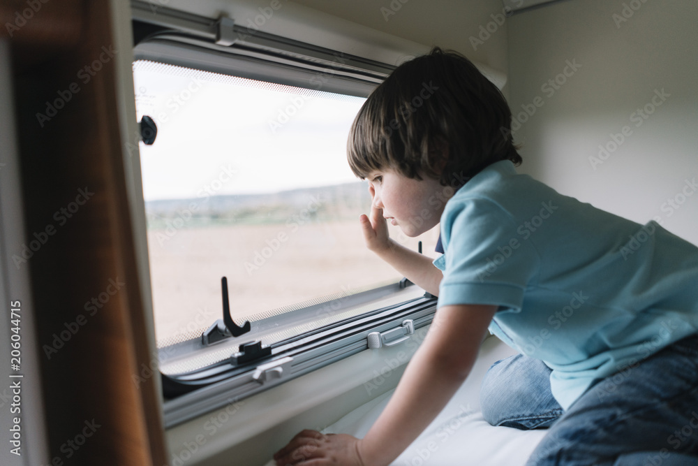 Little boy peeping out of the motorhome window