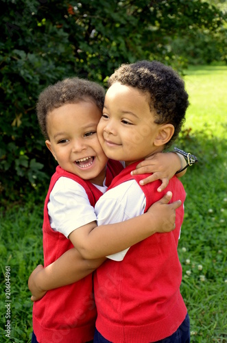 Cute mixed twins brothers hugging each other in the park. Beatiful handsome kids.