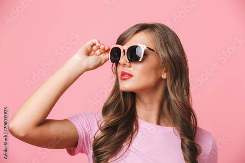 Photo closeup of gorgeous woman 20s wearing fashionable stylish sunglasses looking aside at copyspace, isolated over pink background