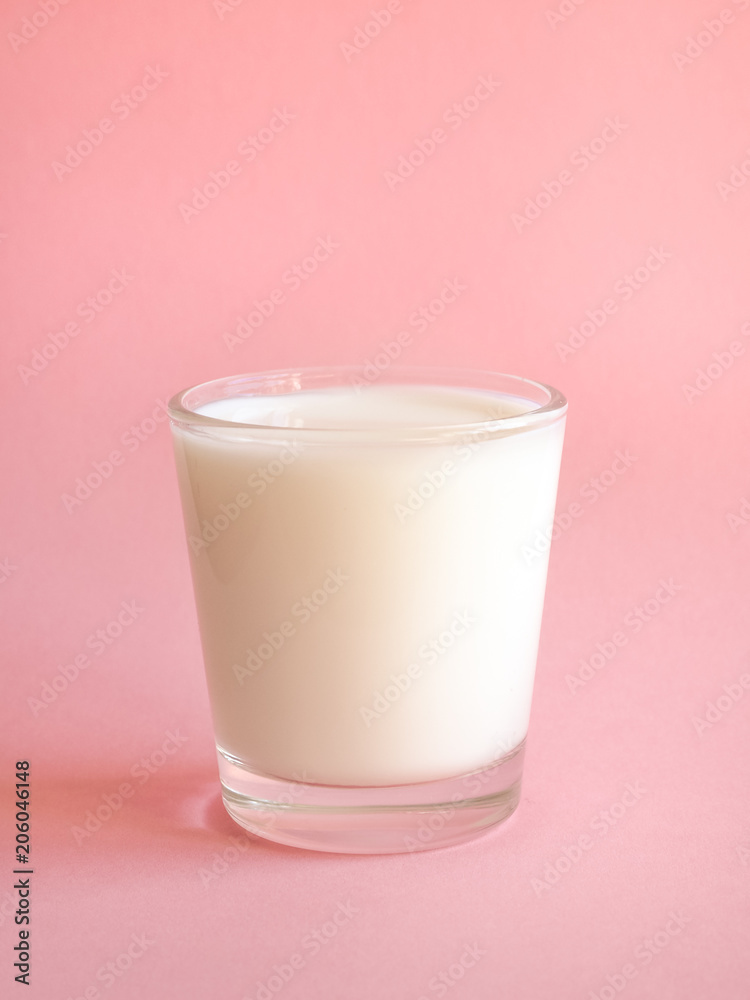 A glass of fresh milk on a pink background.