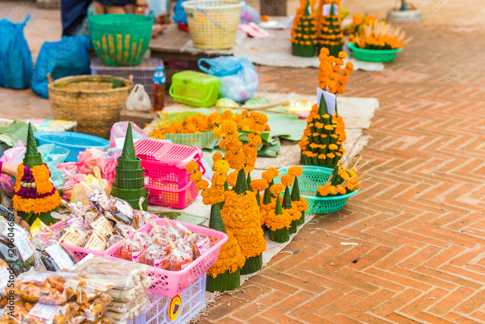 Fototapeta premium Sale of sacrificial offerings from banana leaves and flowers, Luang Prabang, Laos. Copy space for text.