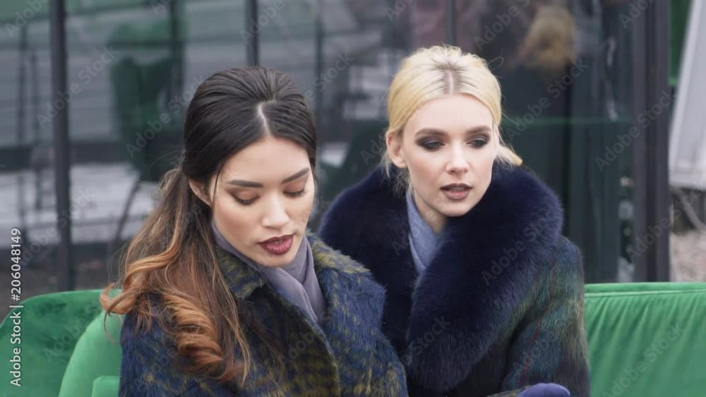 Photosession for the cover of fashion magazine. Photographing the winter collection of coats. girls model sitting on the couch.