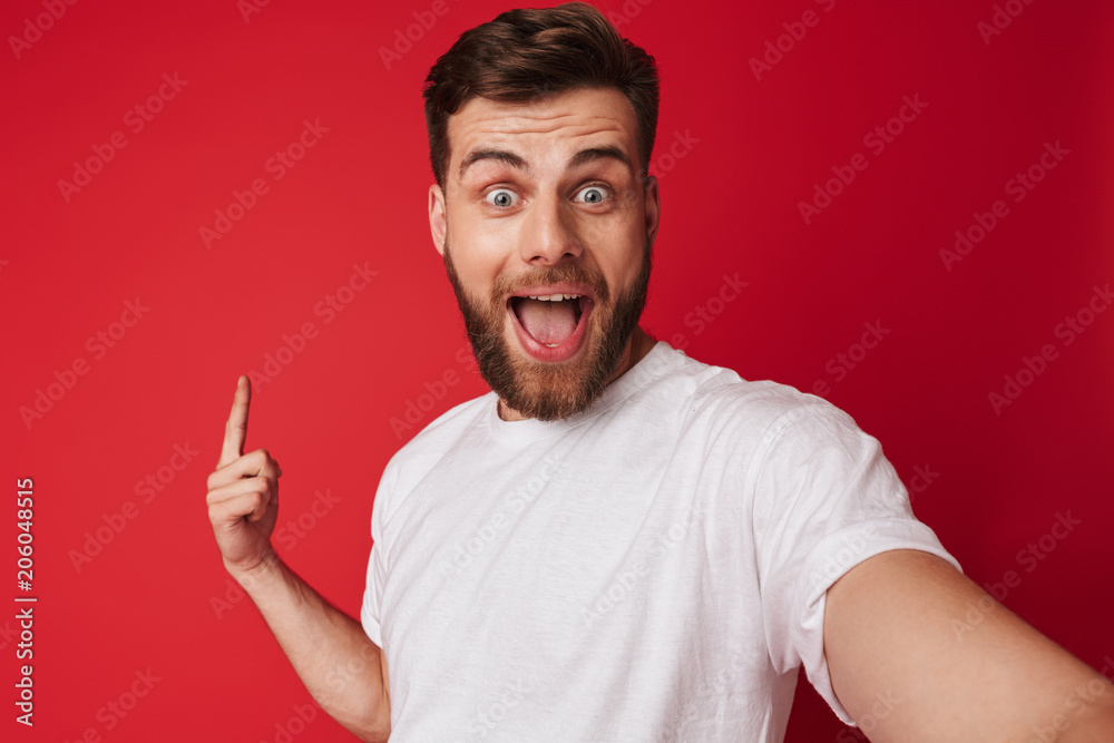 Emotional young man make a selfie looking camera pointing to copyspace.