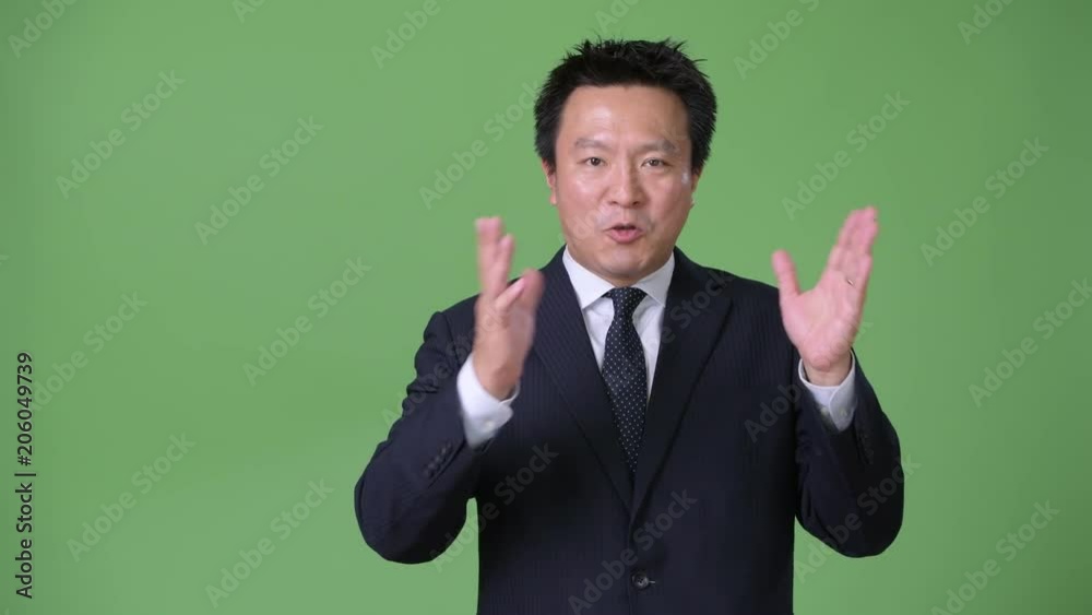 Mature Japanese businessman against green background Mature Japanese businessman against green background