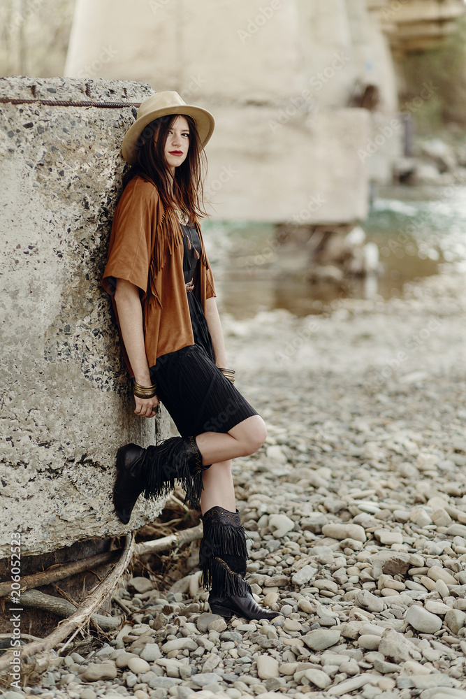 beautiful stylish hipster woman in hat, fringe poncho and boots. boho  traveler girl in gypsy look, near beach in mountains. summer travel.  atmospheric moment. space for text. Stock Photo | Adobe Stock