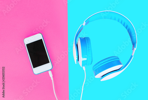 Headphones and white smartphone over colorfu lpink blue background photo