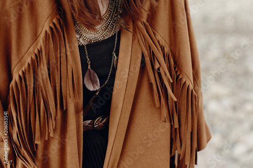 stylish hipster boho traveler woman look. gypsy girl in fringe jacket with feather bronze accessory. wanderlust summer travel. atmospheric moment. space for text. photo