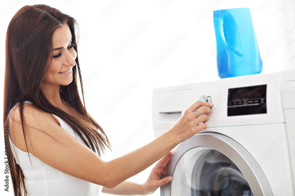 Portrait of young housewife with laundry next to washing machine Portrait of young housewife with laundry next to washing machine