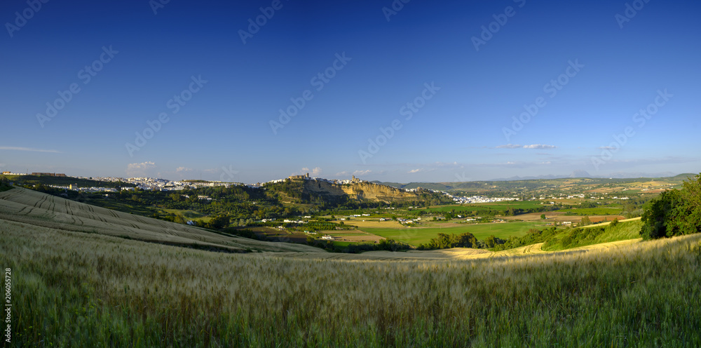 View of Arcos de la Frontera at sunset across a field of wheat from near the A-389, Andalucia, Spain