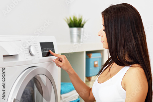 Portrait of young housewife with laundry next to washing machine