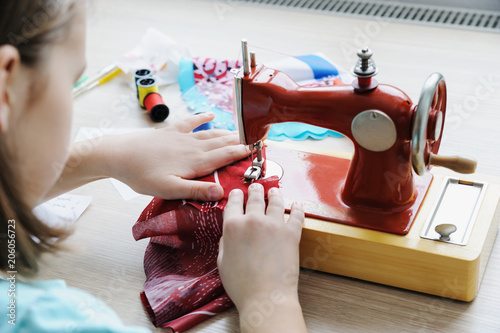 The girl is sewing on a sewing machine.